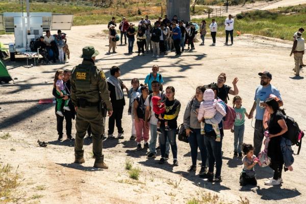 Asylum-seeking migrants lining up near the U.S.-Mexico border in Jacumba Hot Springs, California, waiting to be transported by the U.S. Border Patrol