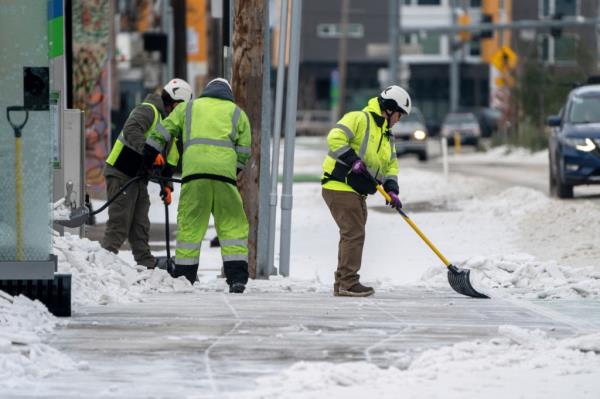 Workers clear snow along 82nd Ave., in Portland, Ore., Sunday, Jan. 14, 2024, a day after a winter storm hit the city with powerful winds, snow, sleet