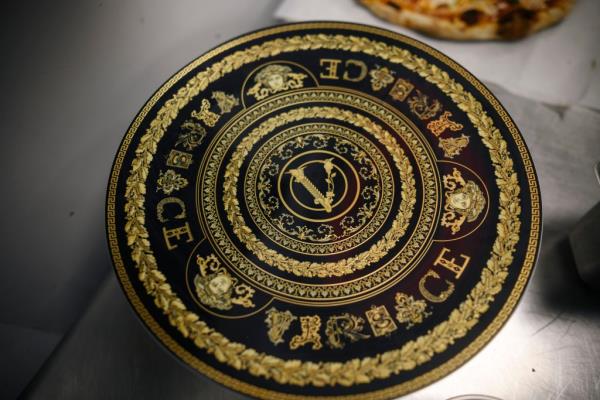 The pizza comes served on authentic Versace plateware.