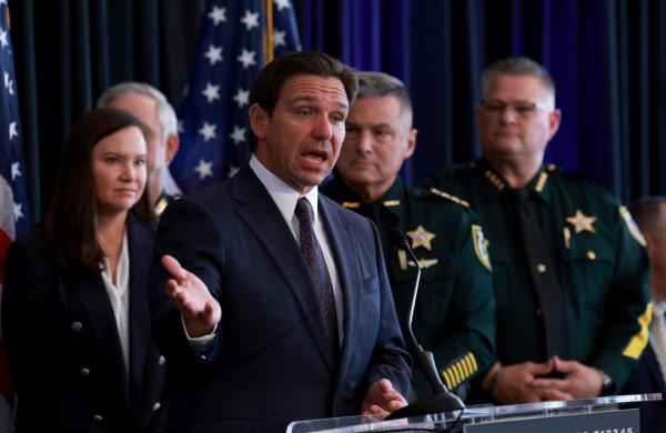 DeSantis speaks at a campaign event in Tampa, raising his hand. 