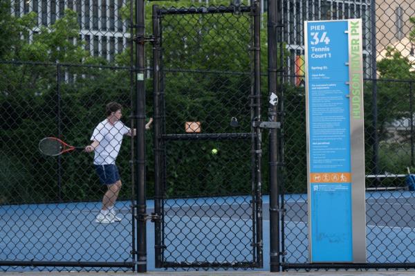 Person hitting a tennis ball on Hudson River Park tennis courts, NY