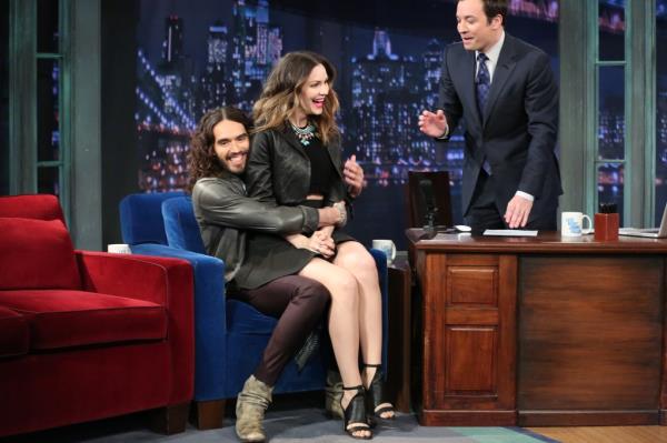 Russell Brand grabs Katharine McPhee, who's sitting on his lap. They're both smiling, but it soon tuned creepy. Host Jimmy Fallon looks on gesturing 