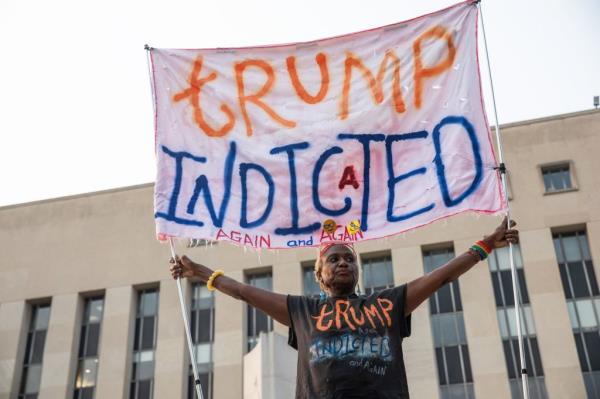 A woman holds a banner a<em></em>bout Trump's indictment in front of E. Barrett Prettyman United States Courthouse on Aug. 2, 2023.