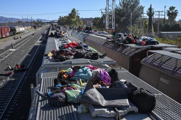 Migrants rest on railroad cars as they wait for a freight train to travel to the U.S. border