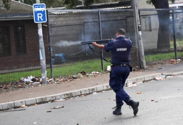 A law enforcement officer fires rubber bullets during their clashes with protesters in Masiphumelele amidst an o<em></em>ngoing strike by taxi operators against traffic authorities in Cape 