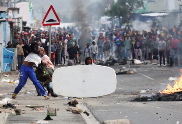 Residents of Masiphumelele throw bottles at law enforcement officers amidst an o<em></em>ngoing strike by taxi operators against traffic authorities in Cape Town, South Africa, August 8, 