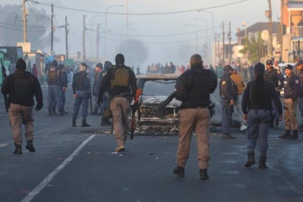 Police and City of Cape Town law enforcement officials stand around a burnt-out vehicle in Nyanga during the o<em></em>ngoing strike by taxi operators over a number of grievances against traffic authorities in Cape Town, South Africa