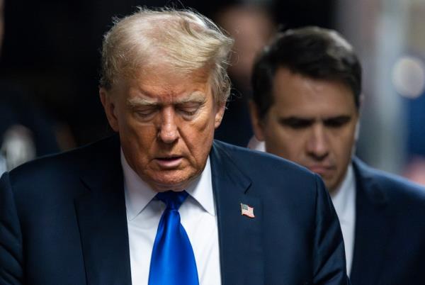 Former U.S. President Do<em></em>nald Trump in a dark suit with a white shirt and blue tie, looking down, arriving at Manhattan Criminal Court for his trial on May 30, 2024