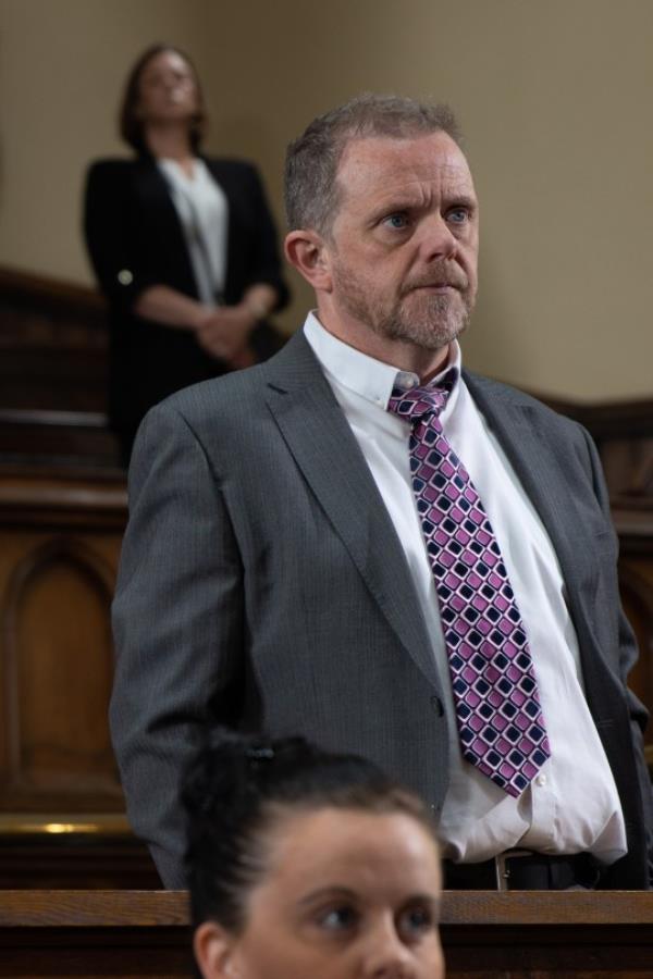 Dan is dressed in a suit and tie as he awaits his verdict in court in Emmerdale