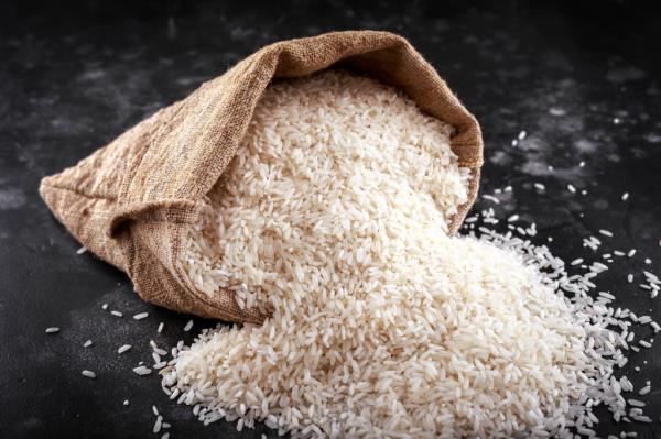 White raw basmati rice in a burlap bag on a black surface