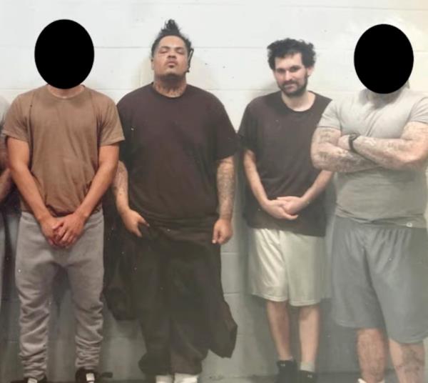 Co<em></em>nvicted former billio<em></em>naire Sam Bankman-Fried with beard, posing in prison with five ex-gang members