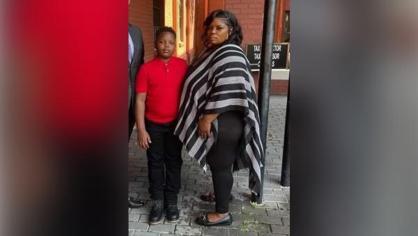 a woman and a boy standing on a sidewalk