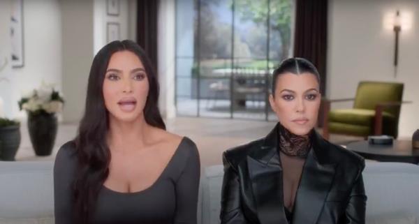 Kourtney and Kim Kardashian sitting next to each other on a couch. 