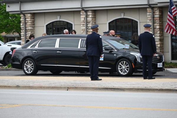 a black limousine outside a funeral home with uniformed officers as mourners attending the wake and visitation for fallen Chicago Police Department Officer Luis Huesca.