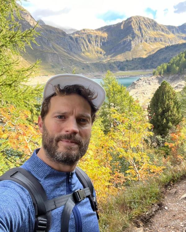 Jamie Dornan smiling in nature. 