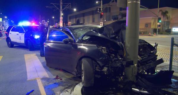 A sedan carrying a family of four is seen wrapped around a power pole in Los Angeles, with blood on the ground, after a violent Sunday crash