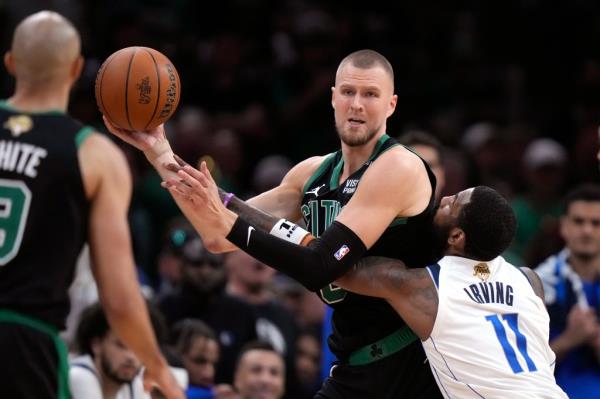 Celtics center Kristaps Porzingis looks to pass while defended by Dallas Mavericks guard Kyrie Irving