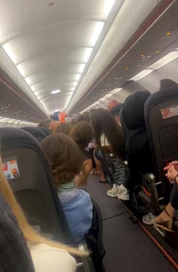 Passengers o<em></em>nboard the flight are pictured listening to the announcement.