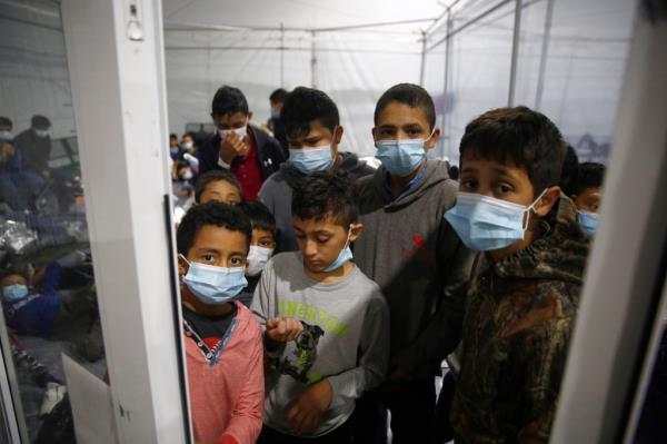 Young children look out from inside a pod at a Border Patrol detention center.