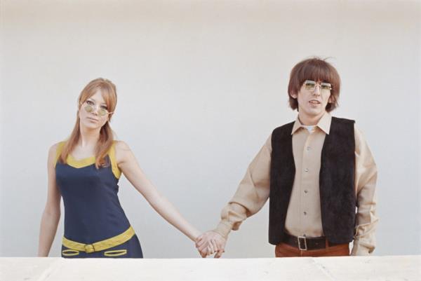 Pattie Boyd holding hands with George Harrison, both in sunglasses