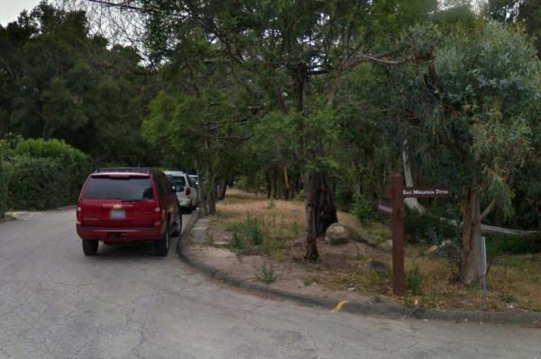 Cars parked on the side of the road near the trail. 