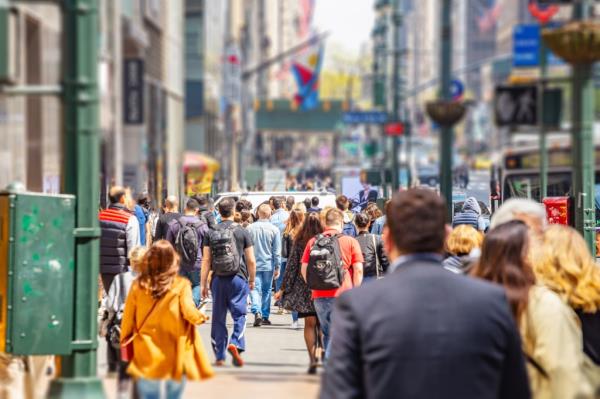 Crowded Manhattan streets with high buildings, cars, and people walking on a sunny spring day