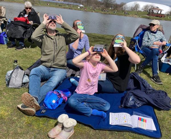 Glenn and Heather Reeher with their daughters Riley and Emma trying out eclipse viewers near a lake in Norristown, Pennsylvania