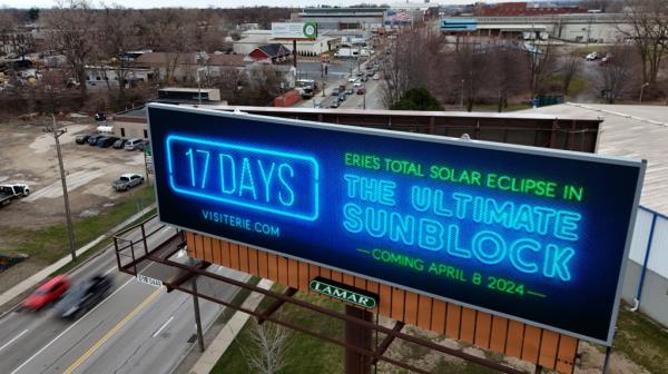 A billboard in Erie, Pennsylvania advertising the upcoming total solar eclipse on April 8, featuring blue and green text.