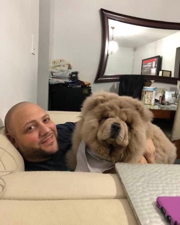 Anthony Russo laying on a couch with his beloved Chow Chow dog, Panda