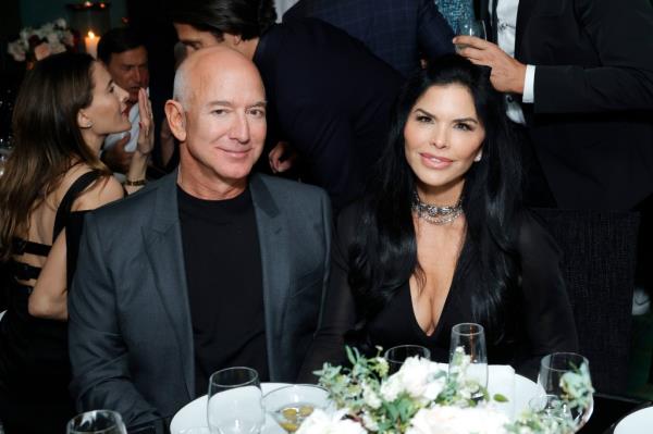 Jeff Bezos and Lauren Sánchez sitting at a table at the CHANEL and Charles Finch Annual Pre-Oscar Dinner in Beverly Hills, California.