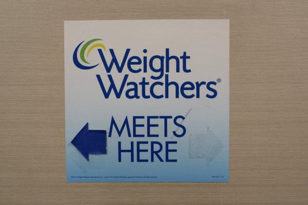 Sign for Weight Watchers displayed on a gray wall in New York.