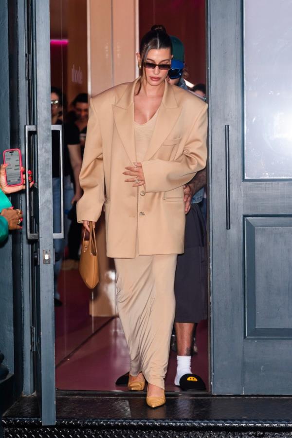 Hailey Bieber in a suit and skirt, carrying a camel-colored handbag, attending a pop-up for Rhode in SoHo, New York City on June 23, 2024.