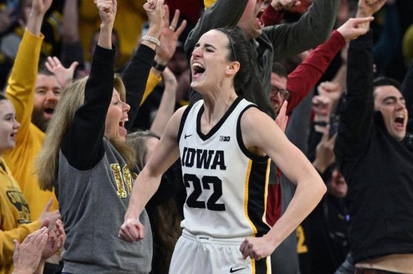 Iowa Hawkeyes guard Caitlin Clark (22) celebrating with fans after breaking NCAA women's all-time scoring record during the game against Michigan.