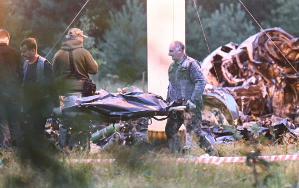 People carry a body bag away from the wreckage of a crashed private jet, near the village of Kuzhenkino, Tver region, Russia, Thursday, Aug. 24, 2023.