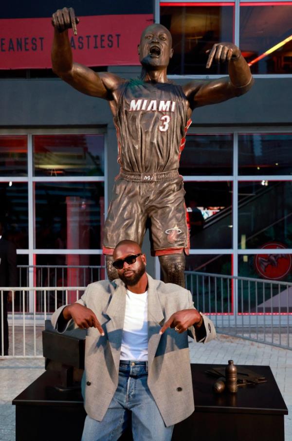 Dwyane Wade, former Miami Heat player, posing with his statue at the Kaseya Center in Miami, Florida