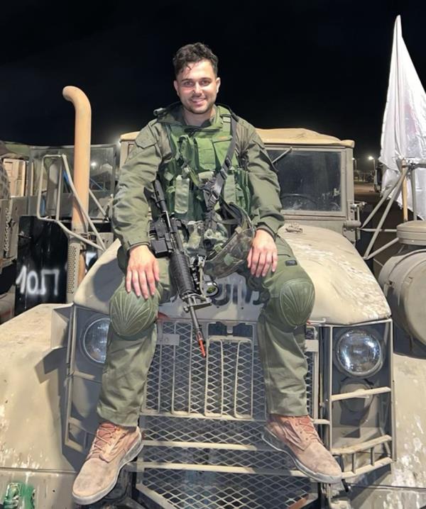 Chanoch Eli Berman sitting atop a truck in his military fatigues