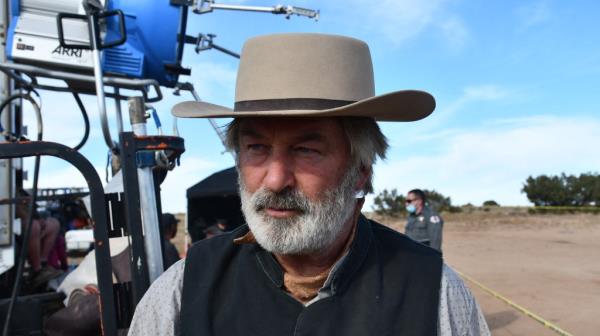 Alec Baldwin in costume in a cowboy hat seen here on the set of rust with an officer or security guard behind him</p>

<p>　　