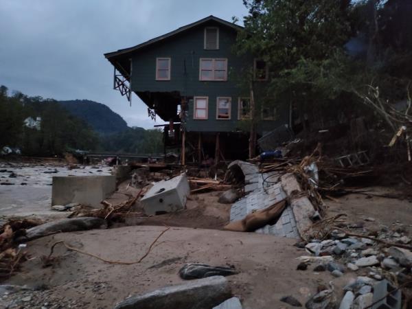 A house teetering on collapse at the edge of a riverbank.