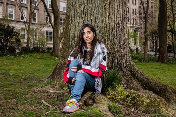 Woman sits in front of a treet.