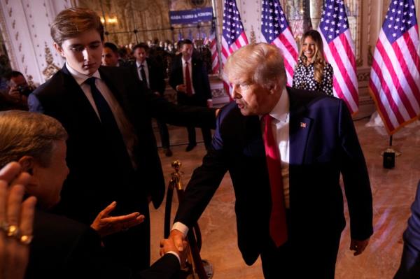 Do<em></em>nald Trump shakes a hand with Barron to the left and Melania behind