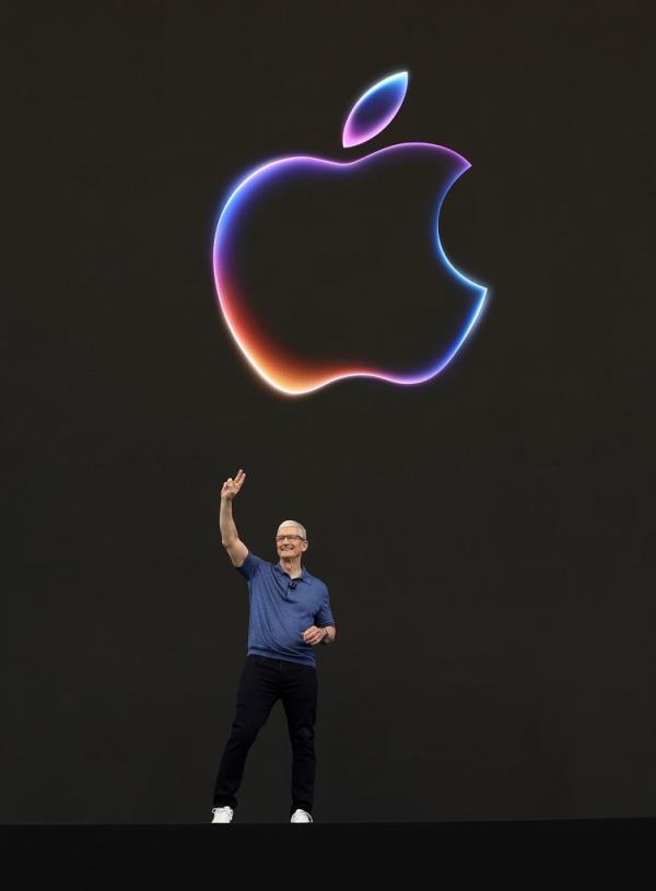 Apple CEO Tim Cook delivering remarks at the Apple Worldwide Developers Conference, standing in front of a large logo.