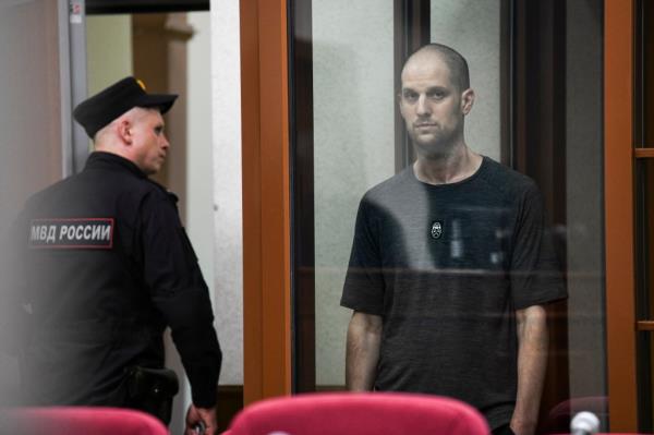 Wall Street Journal reporter Evan Gershkovich standing in a glass cage, listening to the verdict in a courtroom at the Palace of Justice in Yekaterinburg, Russia