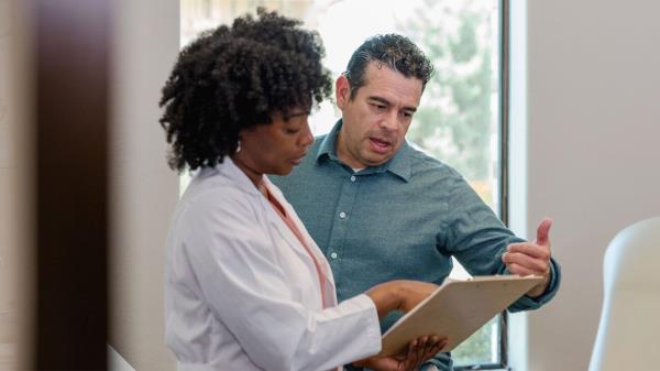 Man in green shirt talks to female physician.